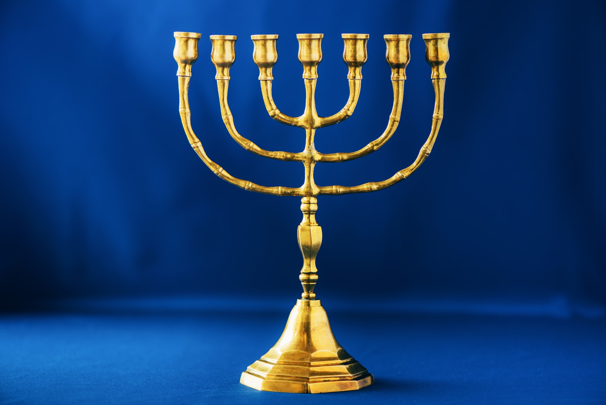 Golden hanukkah menorah on blue background. Jewish holiday banner with copy space. Ancient ritual