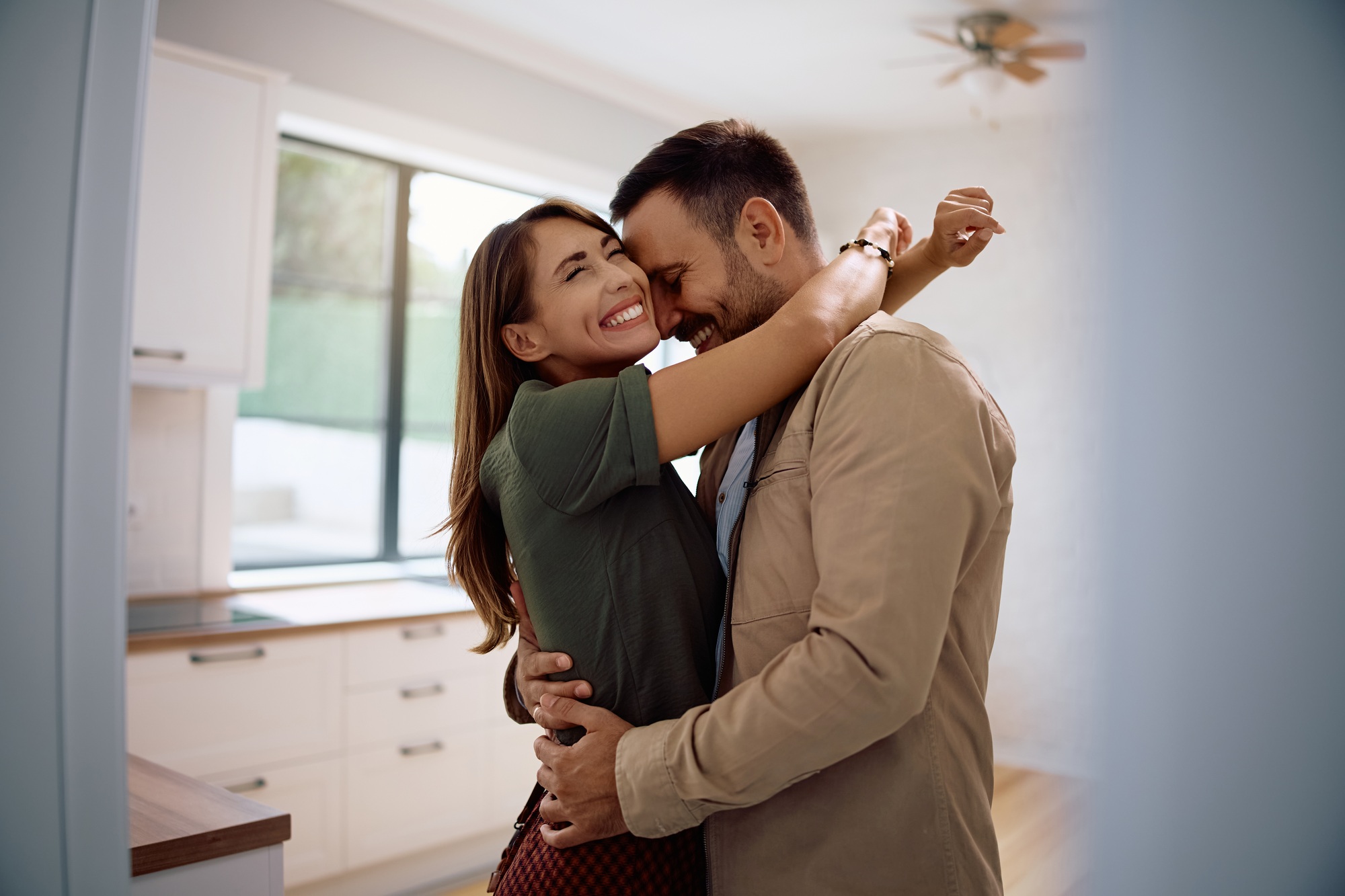 Embraced couple feeling excited after buying their first home.