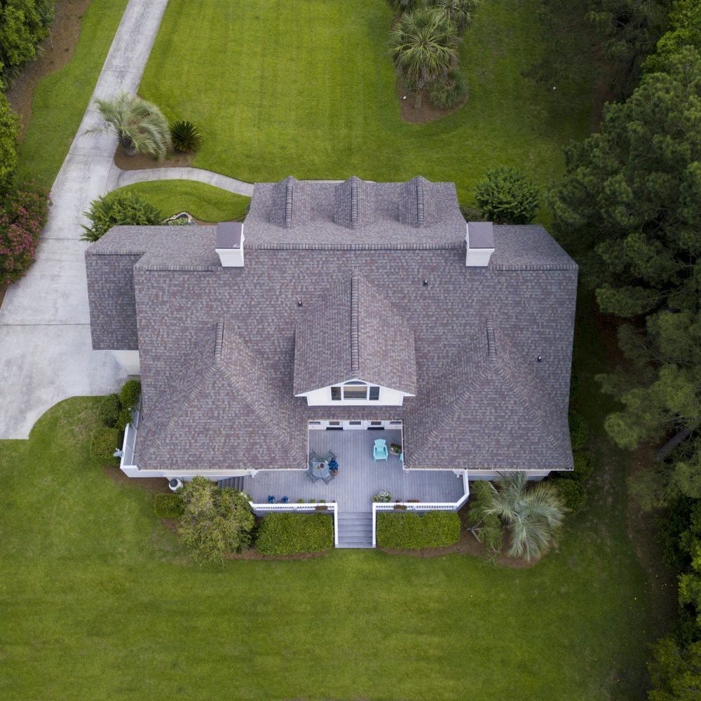 Aerial view of large home with new roof on beautiful property.